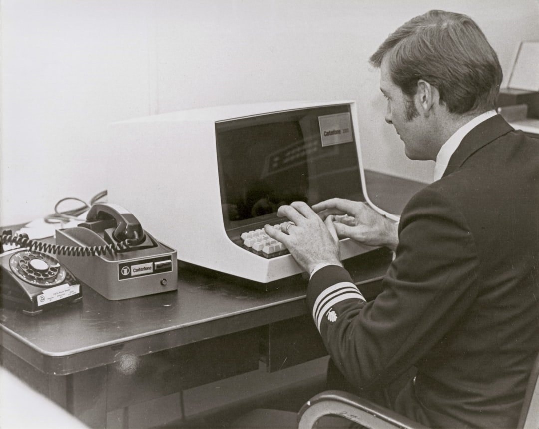 Man in uniform types on vintage computer terminal.
