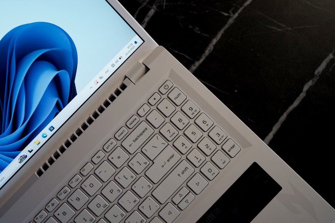 A white laptop with a blue abstract wallpaper open.